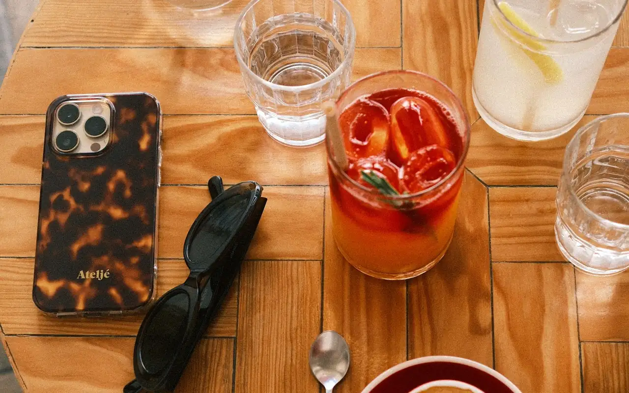 Telefon mobil, ochelari și pahare cu băuturi pe o masă de cafenea