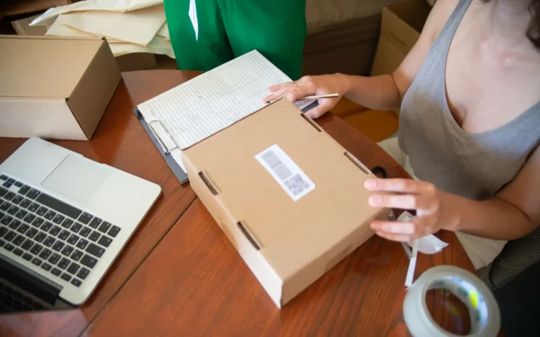 Pregătirea unui colet lângă un laptop și materiale de ambalare